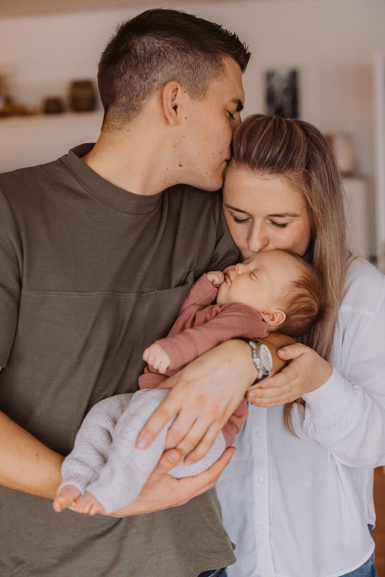 Eltern in schwarz gekleidet halten ihr neugeborenes Baby