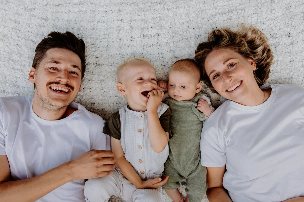 Eltern mit zwei Kindern auf einer Decke im Gras